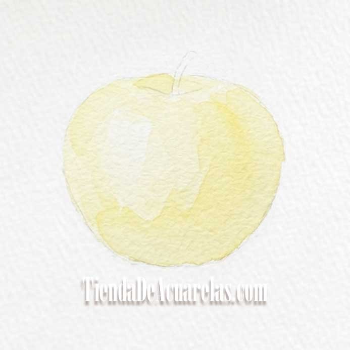 Proceso Manzana pintada por capas en acuarela. Esta primera capa establece la base de luz del objeto, dejando algunas zonas en blanco para los brillos.